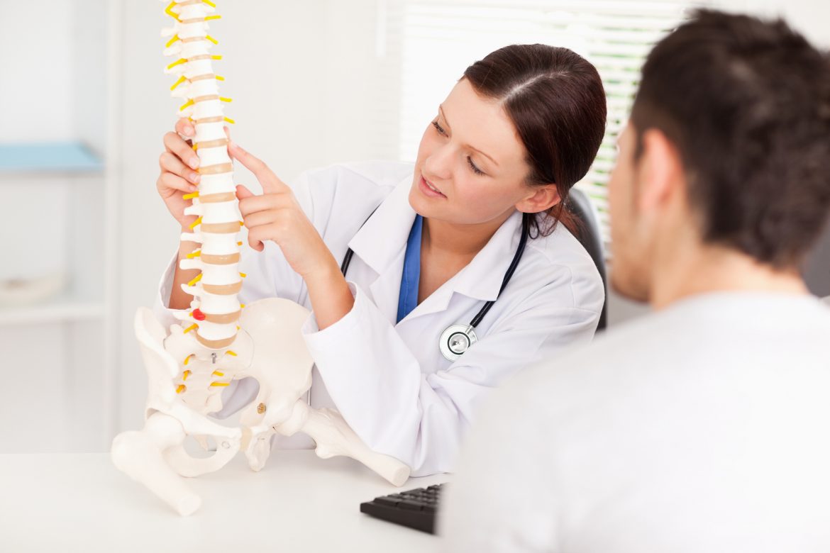 Xcell: Doctor showing a patient a model of a spine